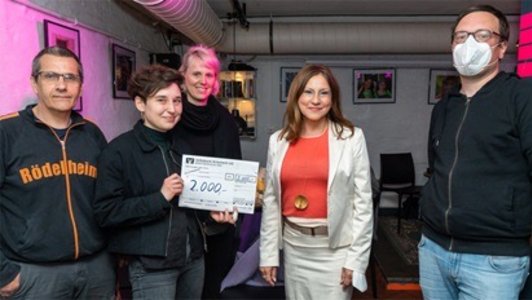 Das Foto zeigt vier junge schwarzgekleidete Leute mit einem großen Scheck über 2000 Euro und in der Mitte in einem weißen Kostüm Bürgermeisterin Dr. Nargess Eskandari-Grünberg